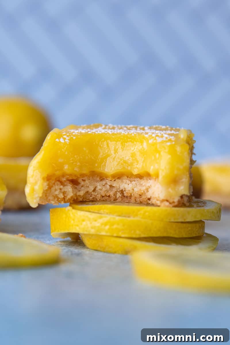 A gluten-free lemon bar with a bite taken out, resting on lemon slices.