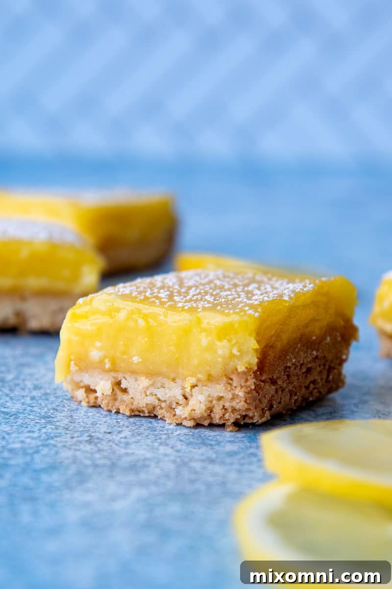 A cut gluten-free lemon square on a blue board with more in the background.