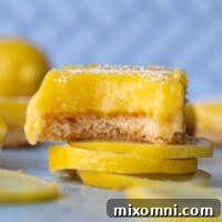 A gluten-free lemon bar with a bite taken out, resting on lemon slices.