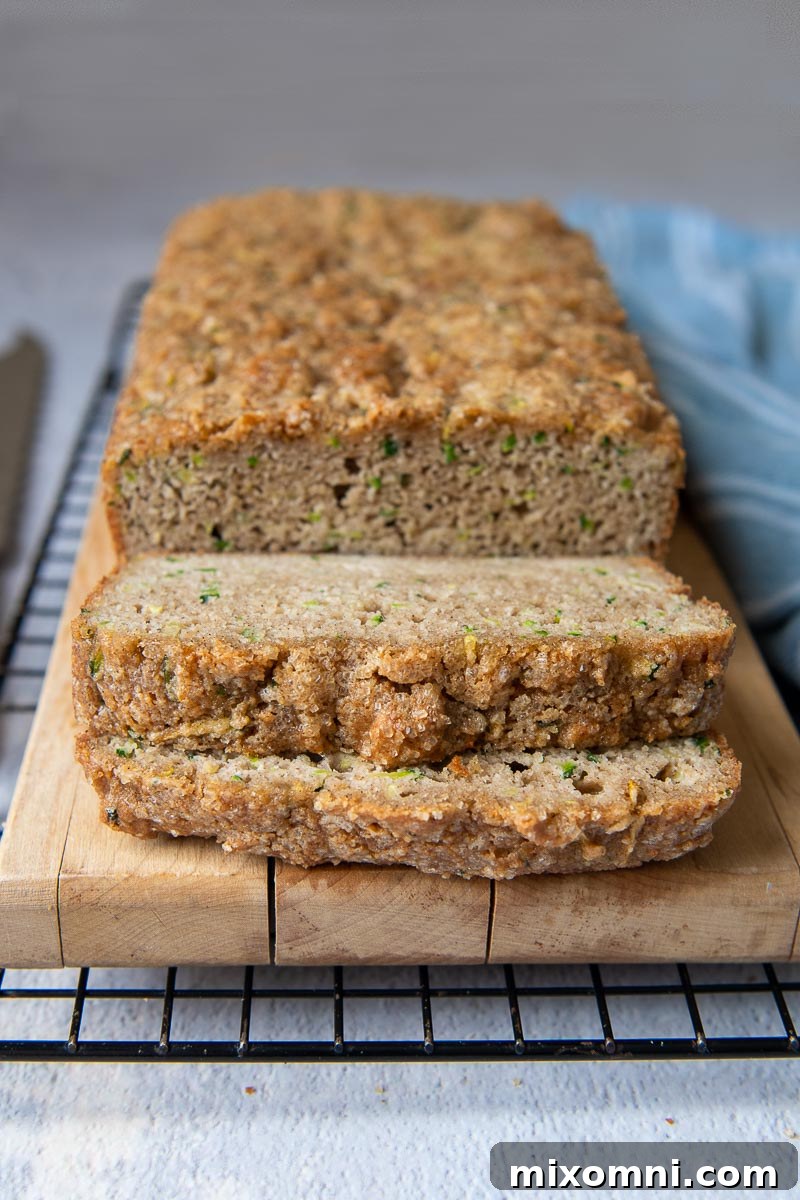 Slices of fluffy almond flour zucchini bread stacked on a wooden cutting board, ready to be enjoyed.