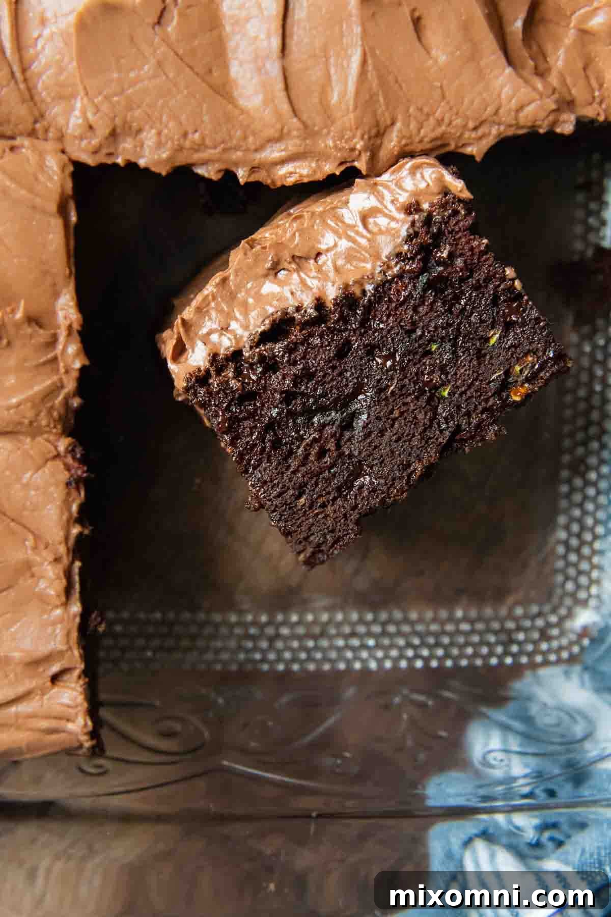 A delectable slice of gluten-free zucchini chocolate cake, standing upright in a baking pan, showing its moist texture.