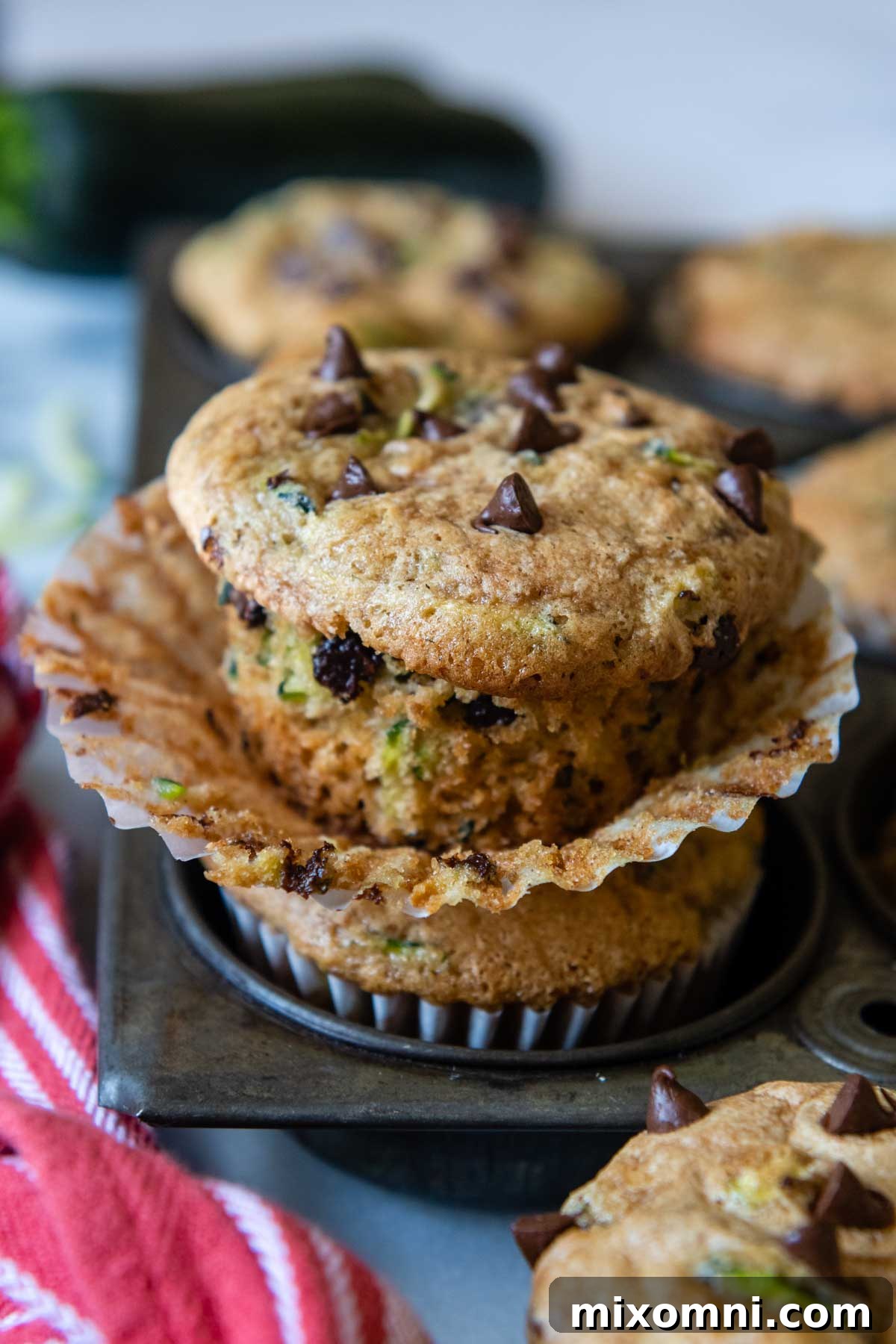A freshly baked gluten-free zucchini muffin, unwrapped from its liner, resting on a vintage muffin pan, showcasing its perfect texture.