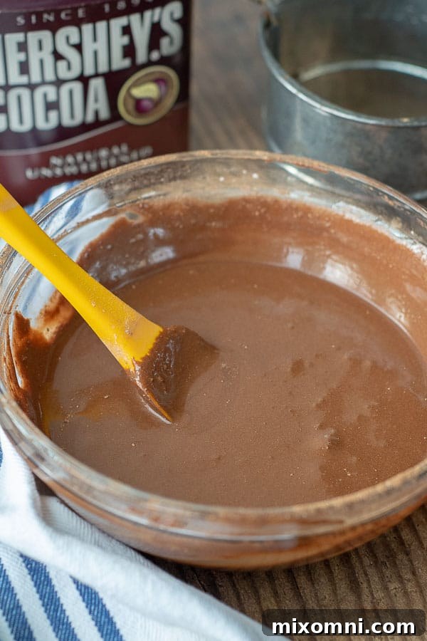 A bowl containing the pre-mixed chocolate base for the whipped cream frosting, with a yellow spoon.