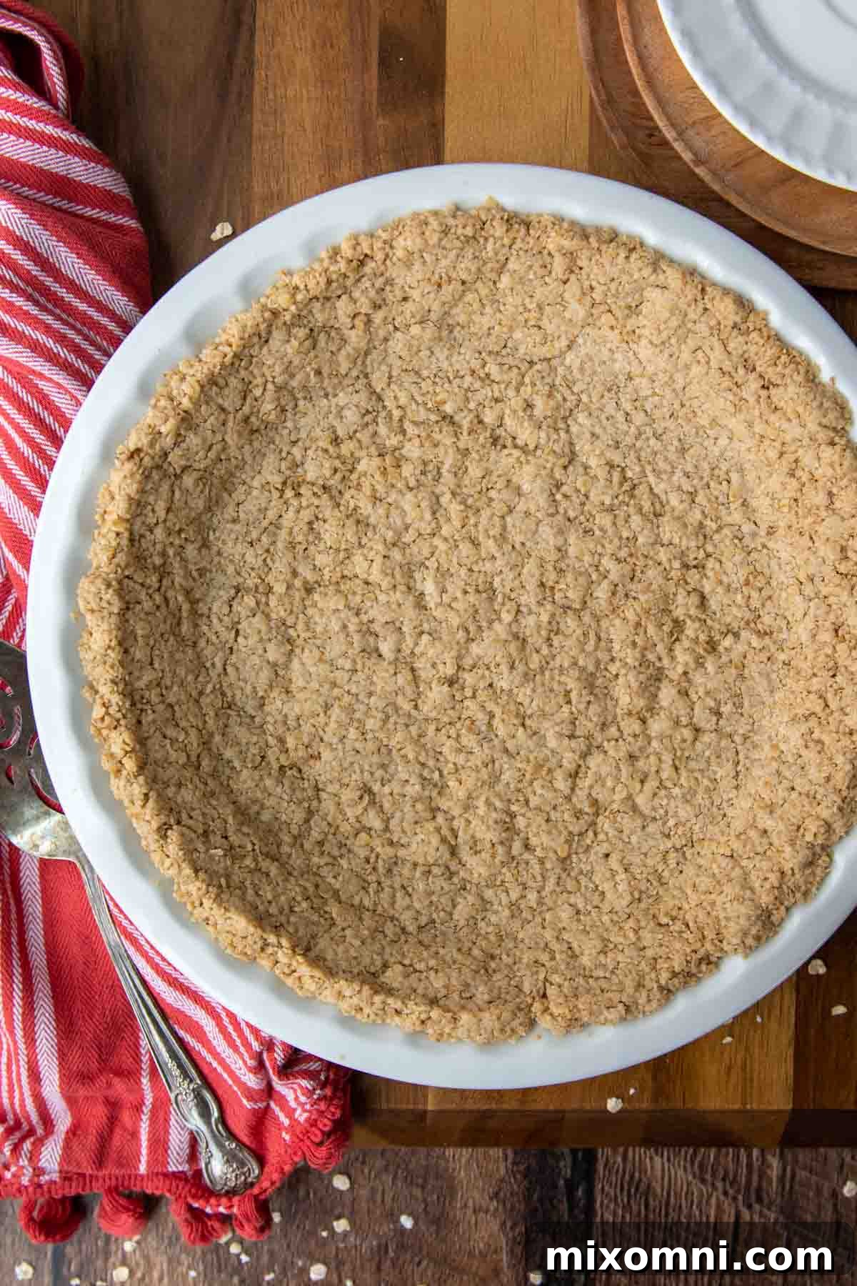 overhead shot of baked oatmeal pie crust in a white plate with a red linen next to it