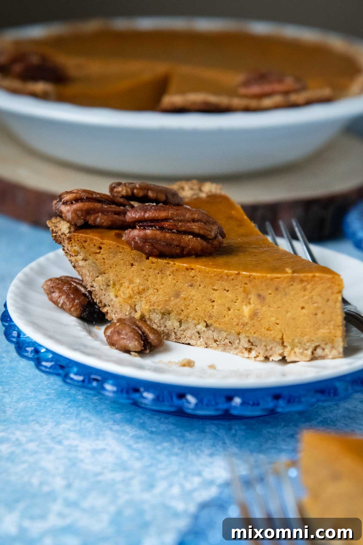 slice of pumpkin pie on a white plate on blue background