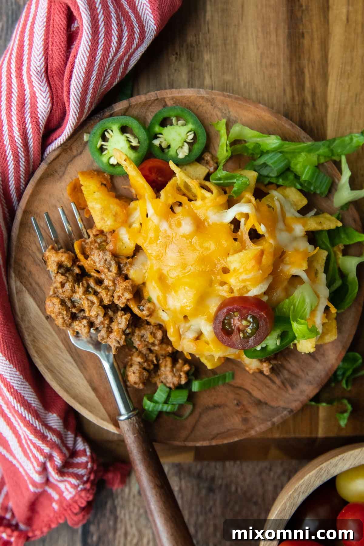 overhead shot of wood plate with a serving of casserole on it and fork scooping up a bite
