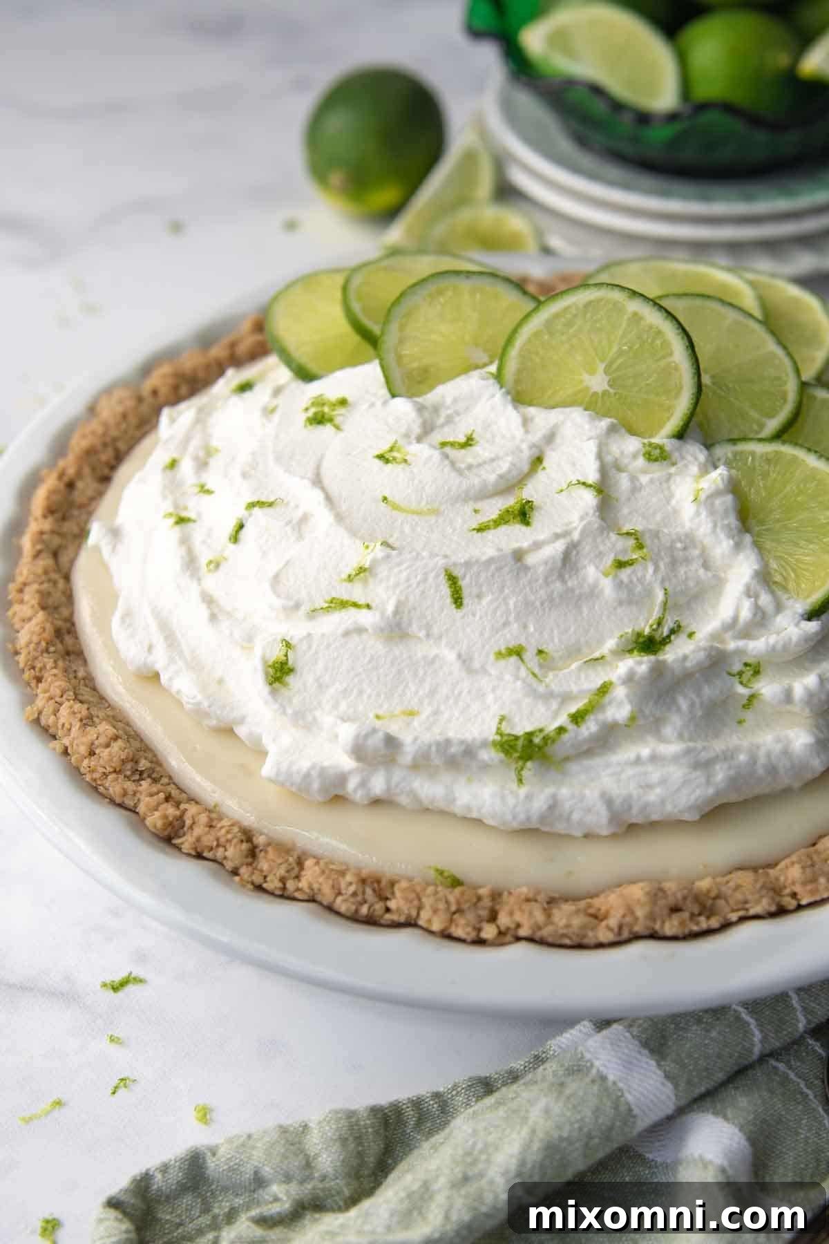 whole gluten free key lime pie in a white pie dish with sliced limes on top