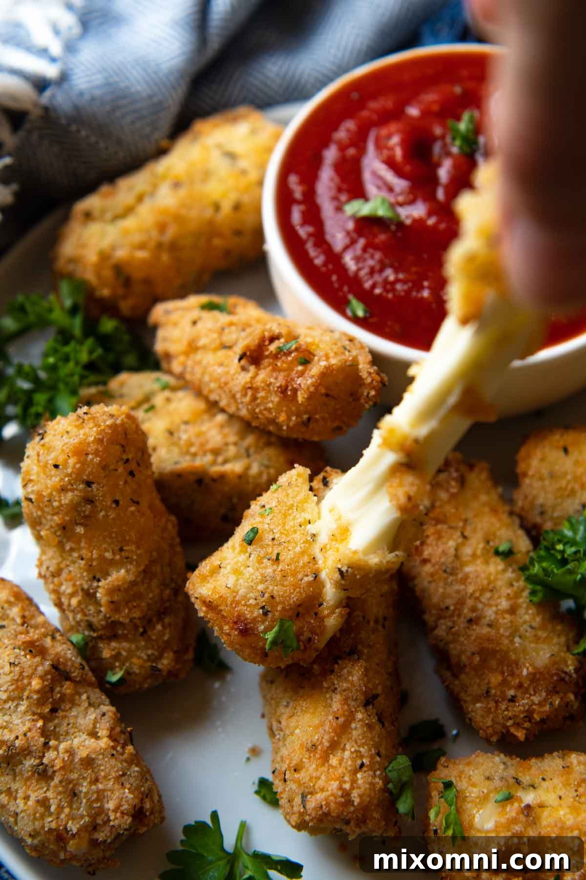 a hand pulling the gluten free mozzarella sticks with cheese pulling out