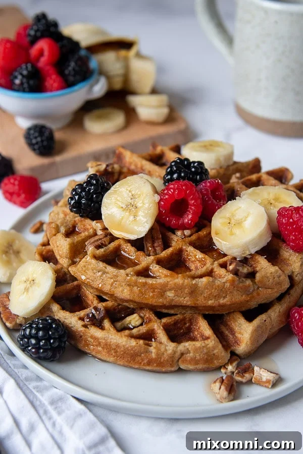 shot of gluten free waffles on a plate with berries, nuts, and bananas on top