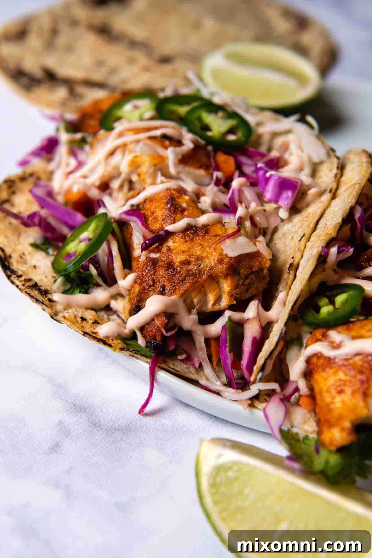 Close-up shot of a single blackened fish taco on a white marble countertop