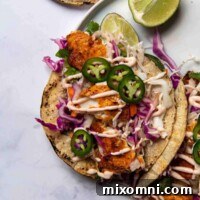 overhead shot of blackened fish tacos on a white plate with cut limes around