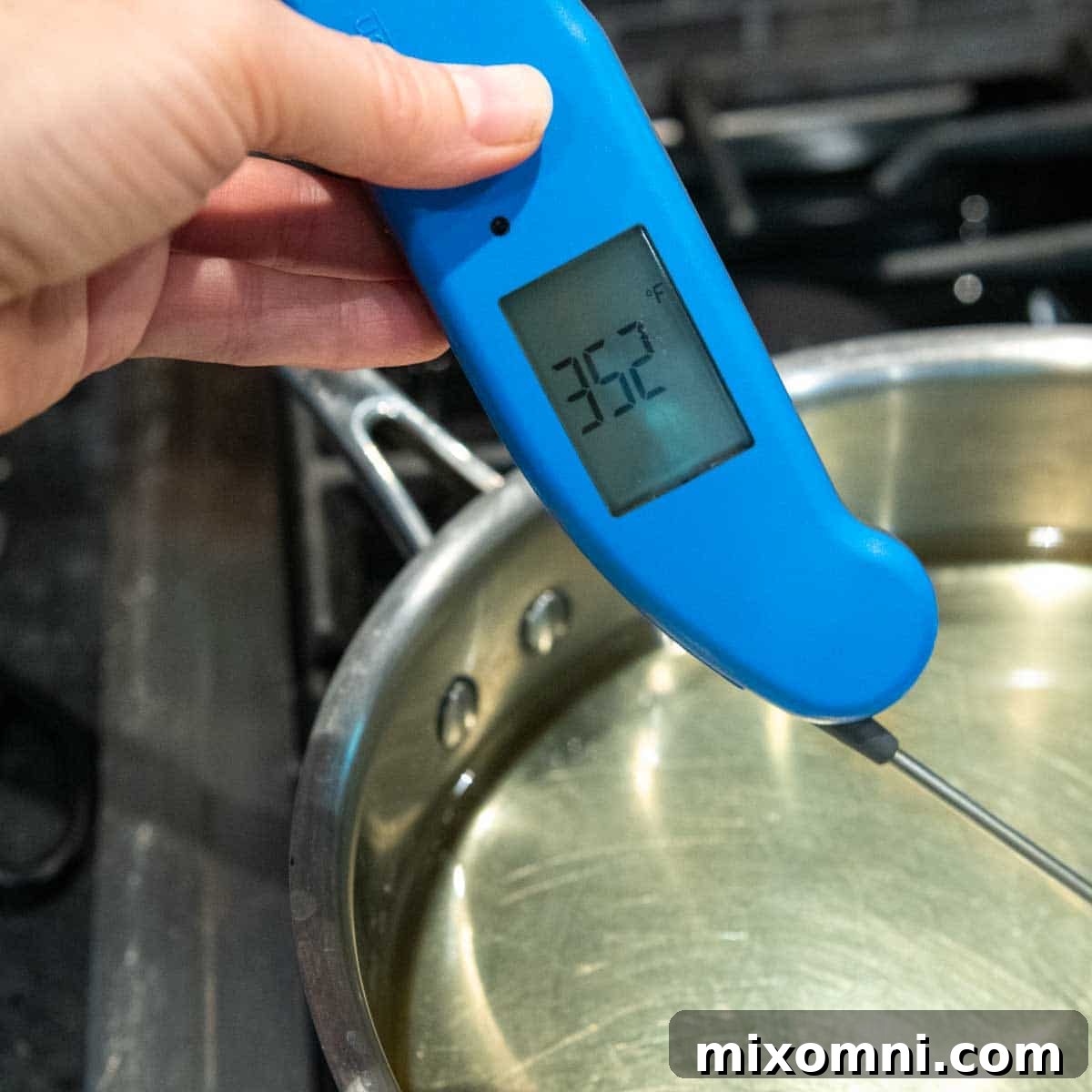 A thermometer accurately measuring the temperature of cooking oil in a deep skillet on the stove.