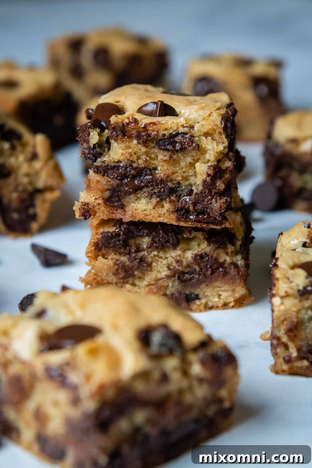 A stack of two gluten-free blondies with melted chocolate chips, surrounded by perfectly cut bars.