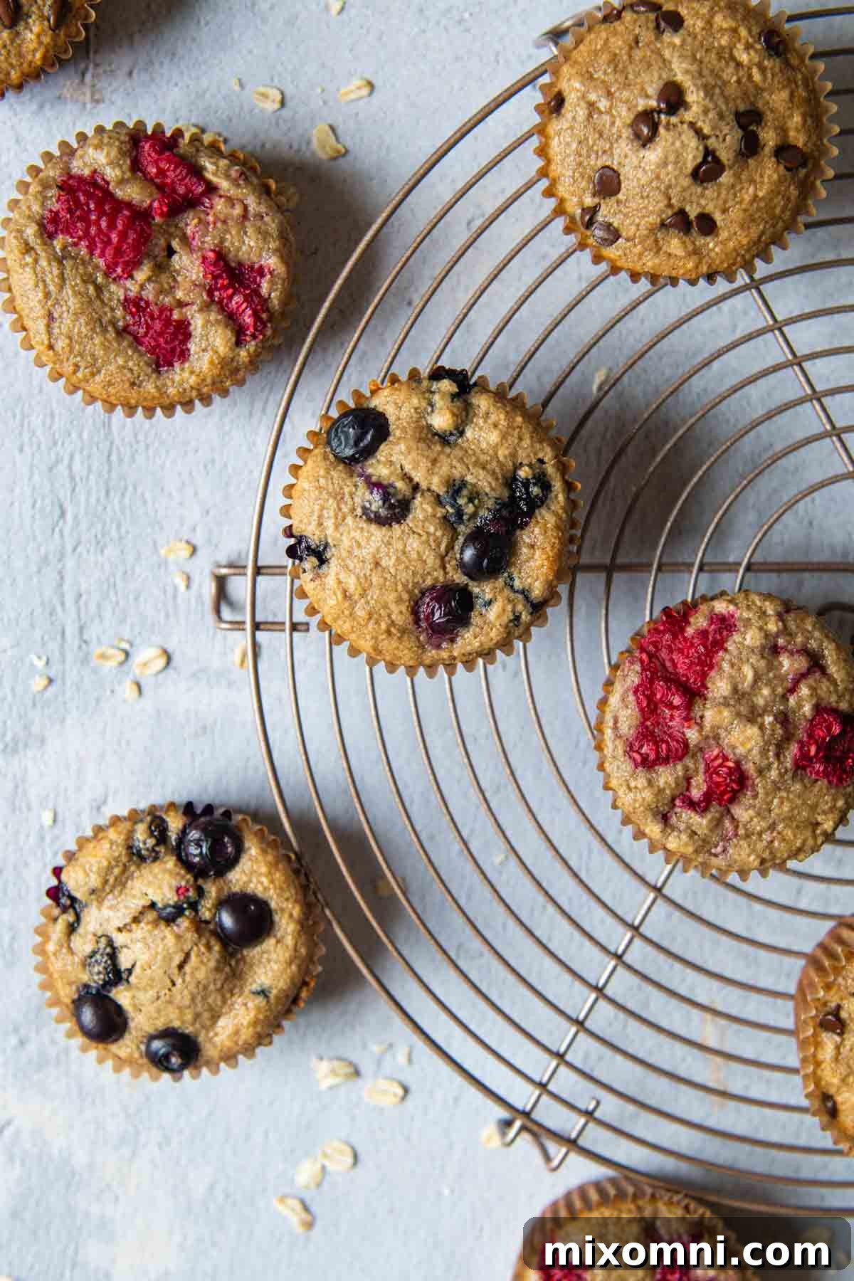 overhead shot of oat flour muffins on a circular cooling rack, showcasing their golden-brown tops and light texture.