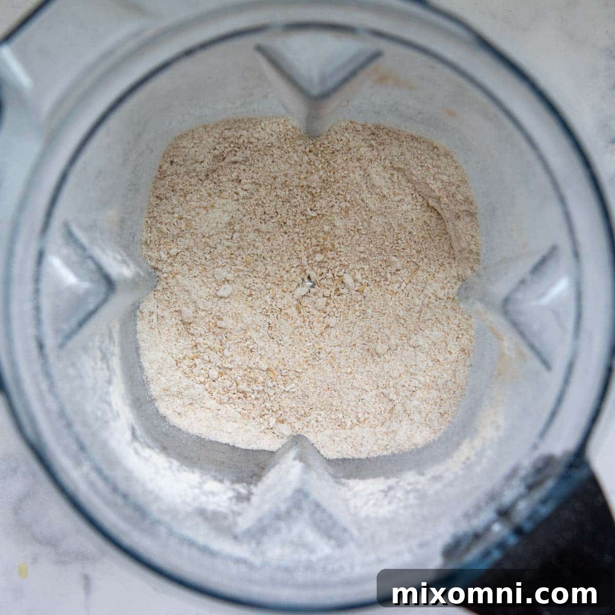 Oats being blended into fine oat flour in a high-speed blender, illustrating the transformation process.