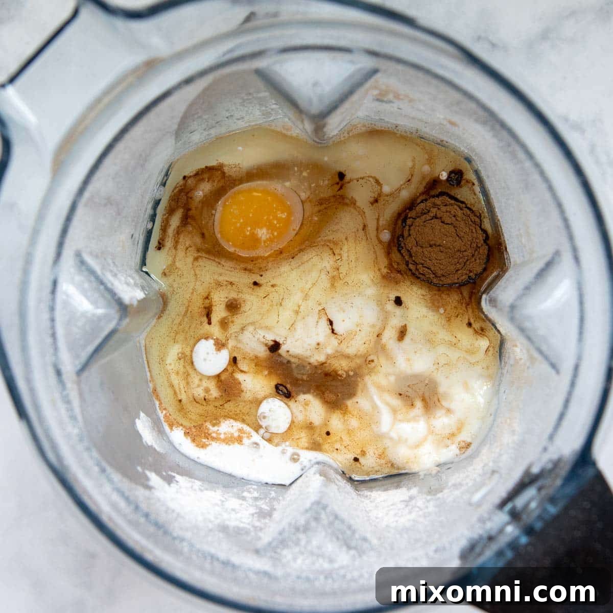 All wet ingredients, including yogurt, milk, and egg, added to the blender with the previously blended oat flour.
