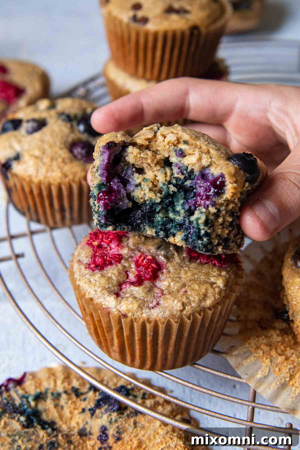 A delicious blueberry oat flour muffin, bitten into and held up, showing its moist interior and blueberry distribution.