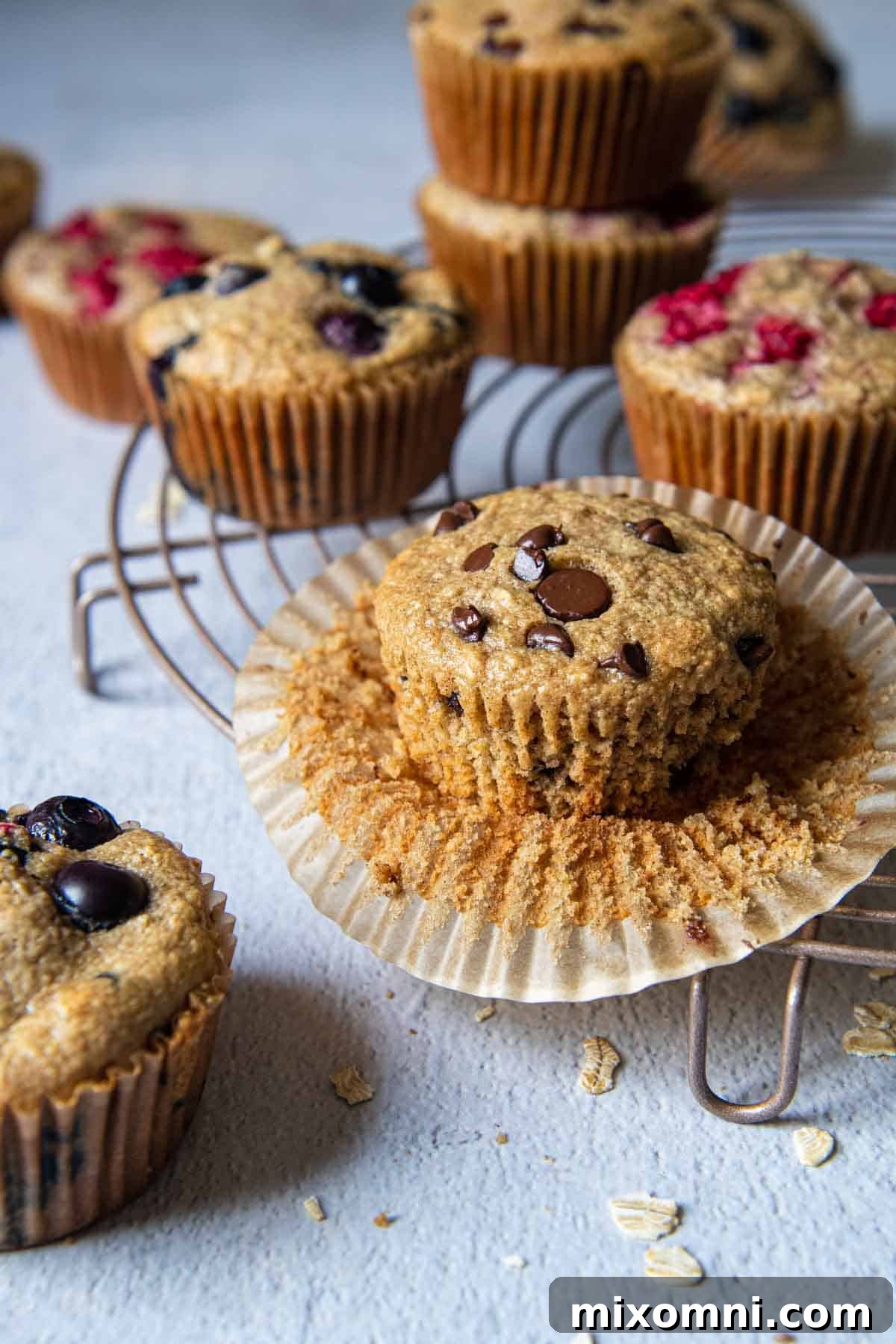 A spread of different oatmeal muffin varieties, including chocolate chip and plain, artfully arranged on a wooden board.