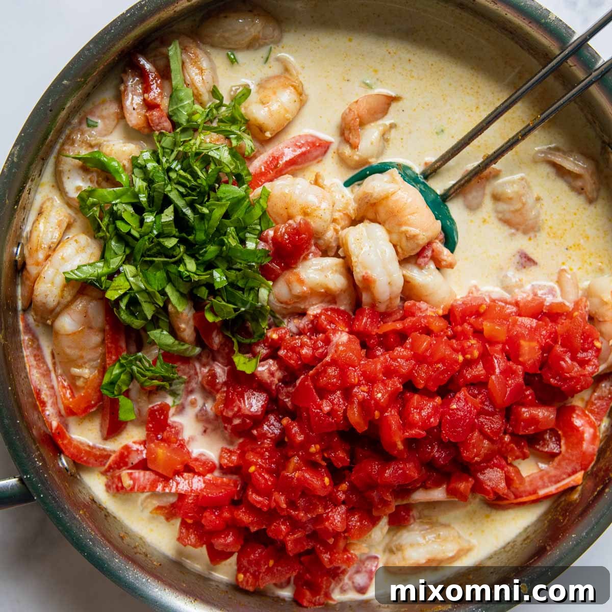 Image showing how to stir in coconut milk, diced tomatoes, and basil, then simmer the coconut shrimp curry.