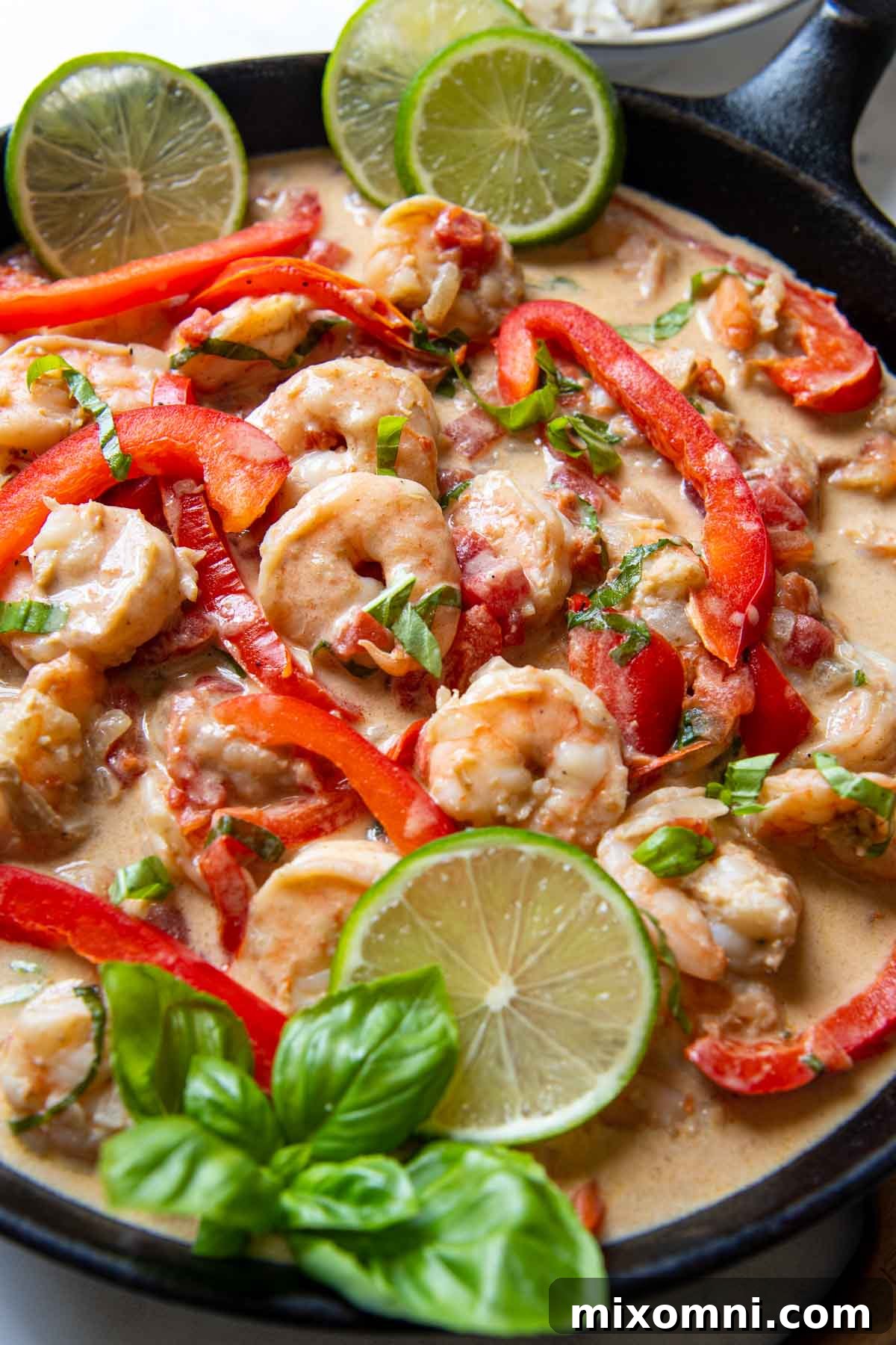 Close up of coconut shrimp with slices of lime and fresh herbs next to it.