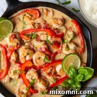 overhead shot of completed creamy coconut shrimp with a bowl of limes and rice next to it