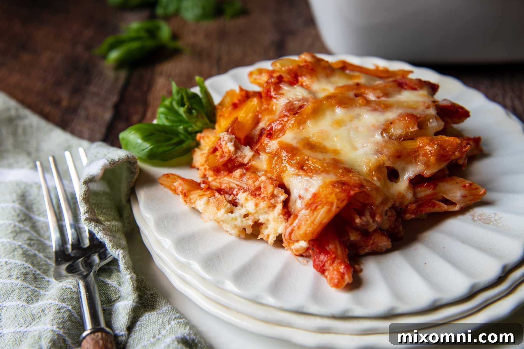 A perfectly portioned serving of meatless baked ziti on a white plate, showcasing its layers of pasta, sauce, and melted cheese.