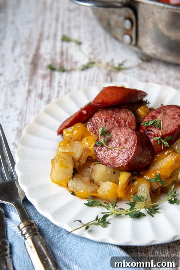 smoked sausage and potatoes dinner on a white plate with fresh thyme sprinkled on top