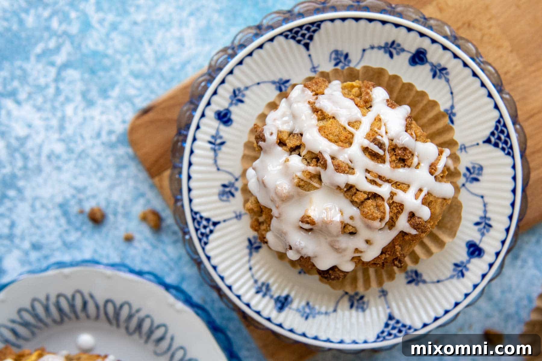 An overhead shot of a freshly baked gluten-free apple crumb muffin, drizzled with sweet vanilla glaze.