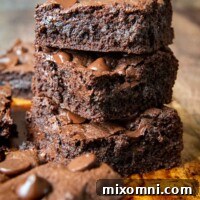 A stack of oat flour brownies on a brown board, showing their fudgy texture.