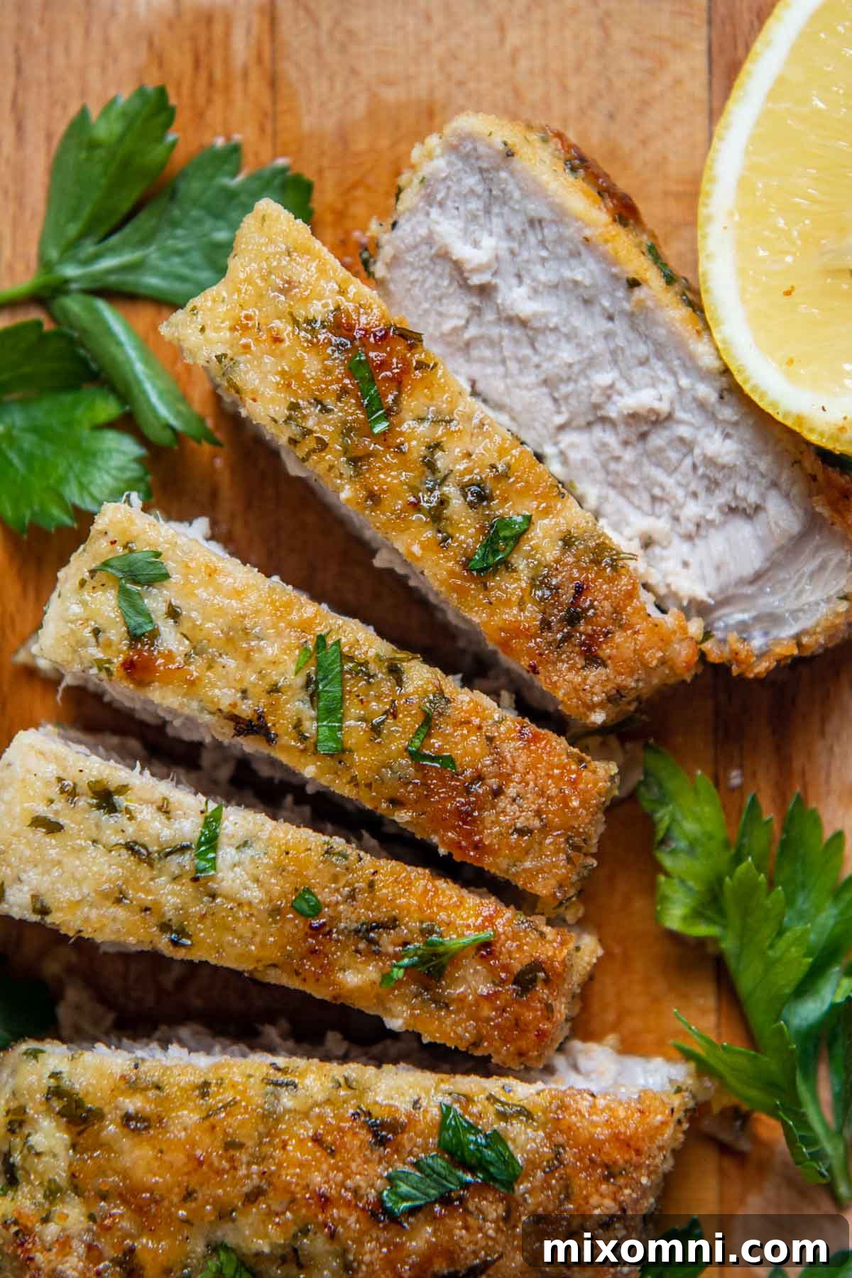 Sliced, oven-fried pork chops with a crispy, low-carb almond flour breading, garnished with fresh parsley.