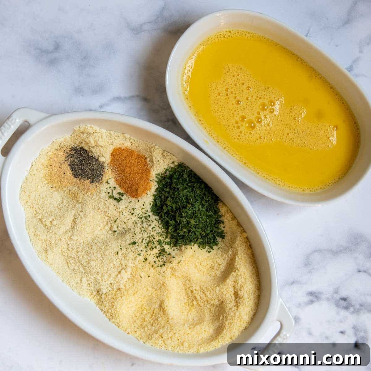 Two bowls prepared for breading: one with a beaten egg, and another with a gluten-free breading mix of almond flour, Parmesan, and spices.