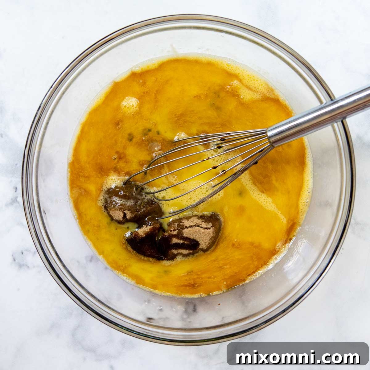 pie filling ingredients being whisked in a large glass bowl.