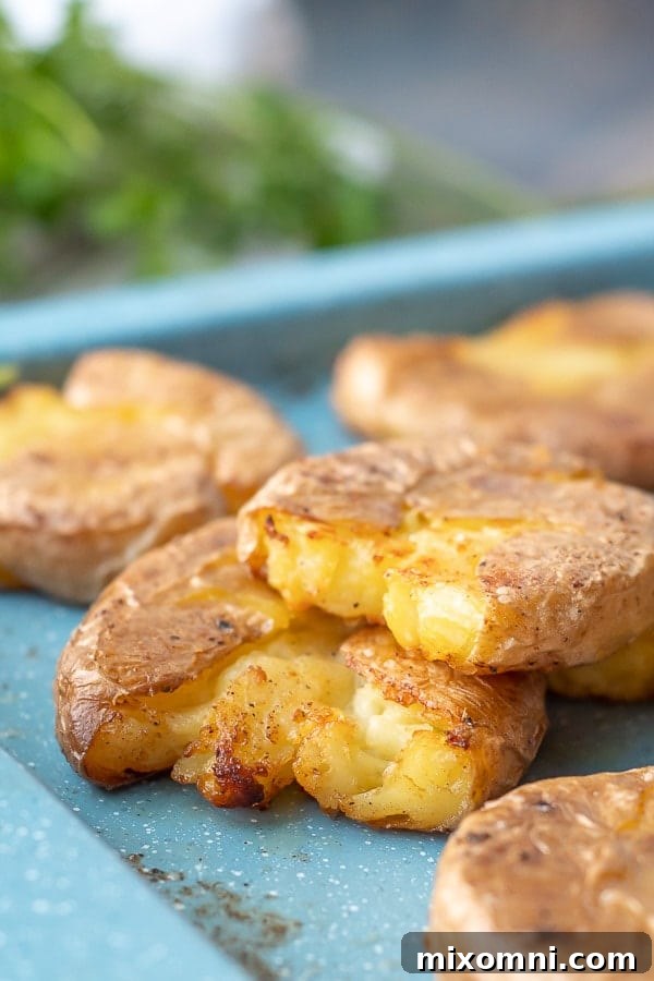 A close-up of two perfectly golden and crispy smashed potatoes, stacked appealingly, ready to be served as a gourmet side.