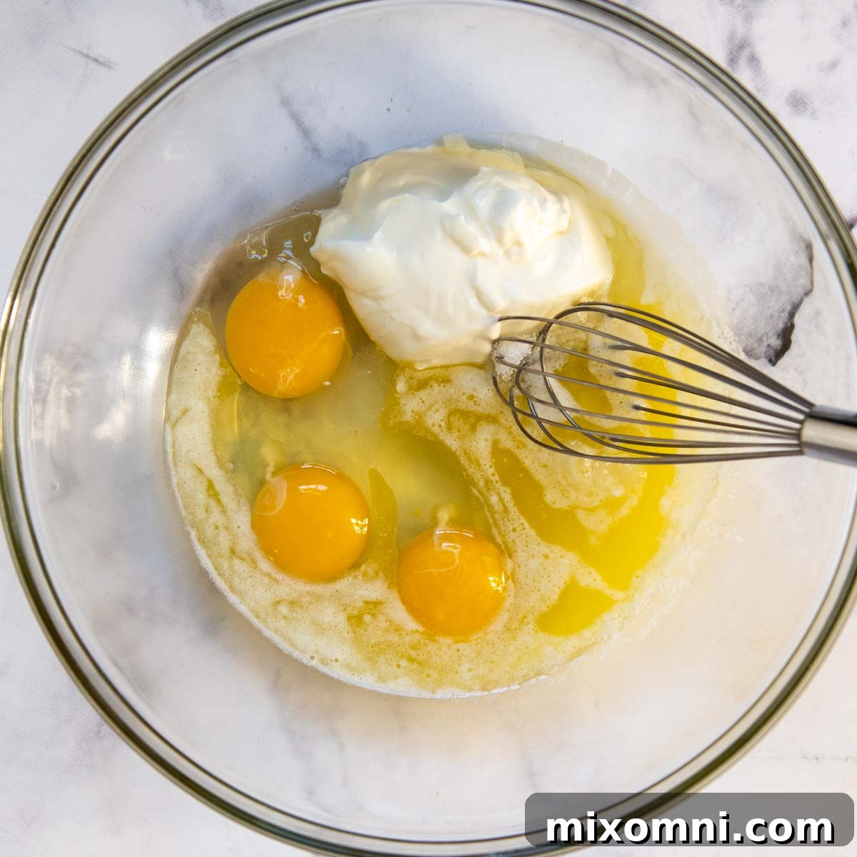 Wet ingredients for gluten-free corn pudding being whisked in a glass bowl