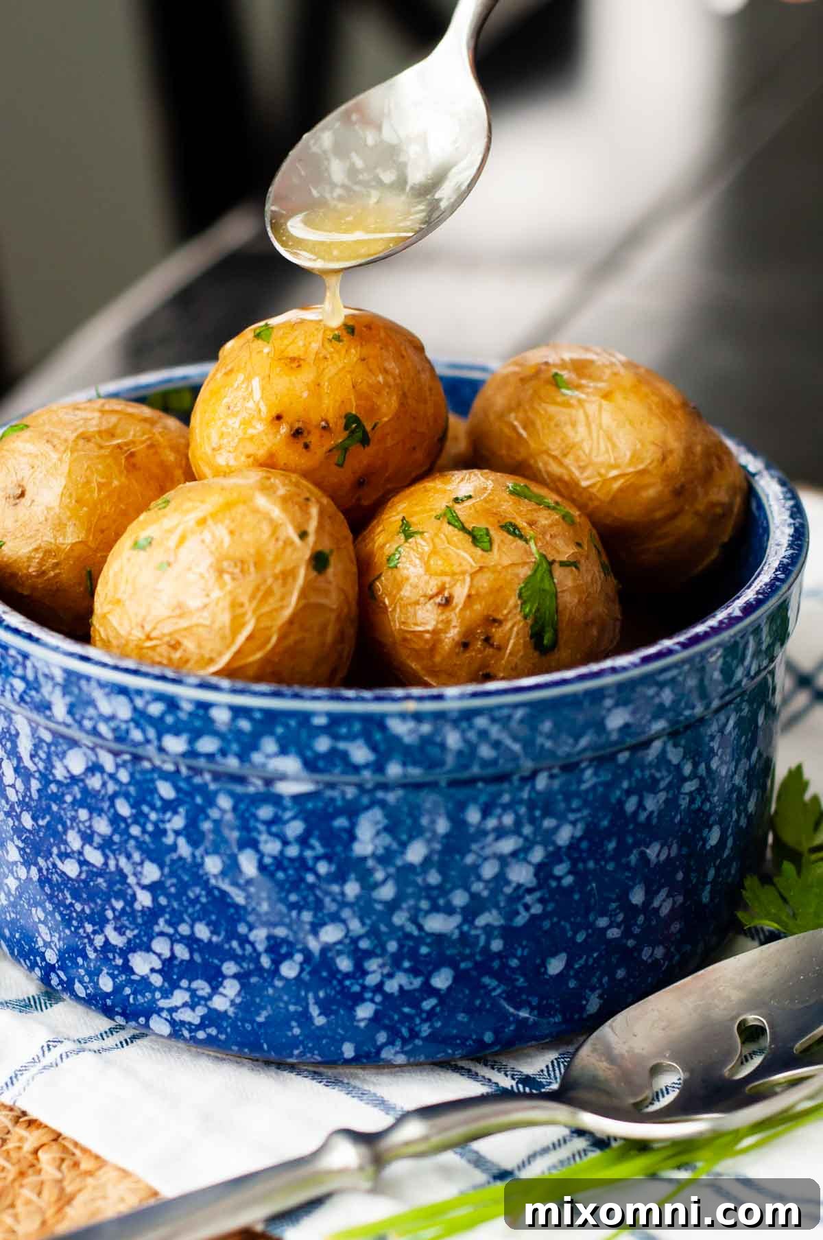 butter being spooned over a bowl of salt potatoes