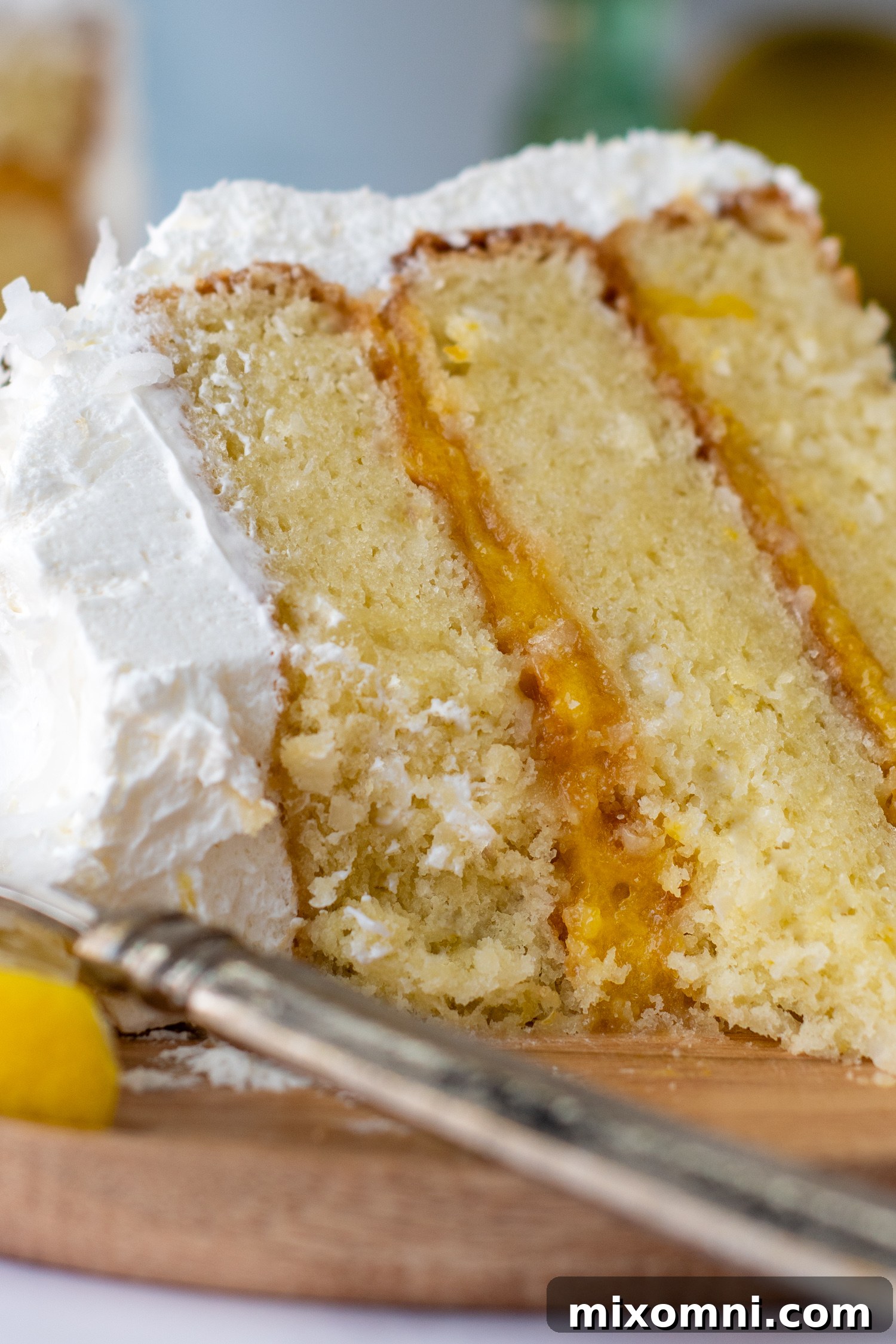 close up of a bitten into slice of cake on a wooden plate.