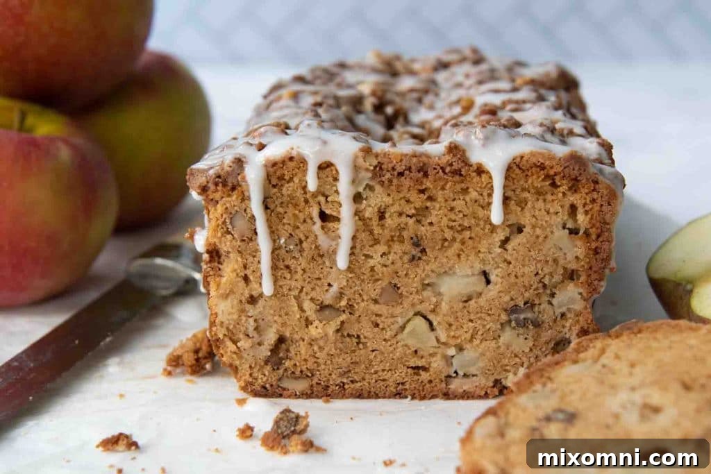 bread with frosting dripping down on cut loaf and apples stacked behind