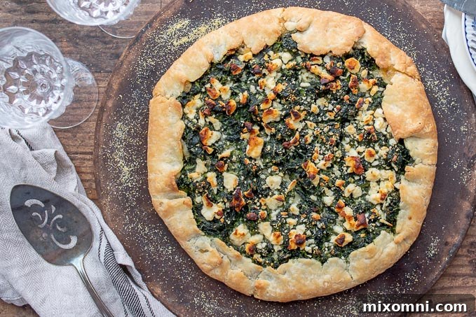 An overhead shot of a freshly baked vegetable tart resting on a rustic baking stone, with a serving spatula nearby.