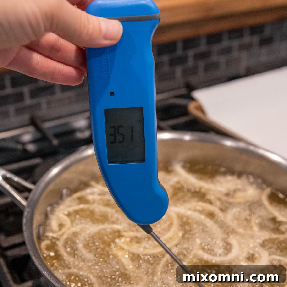 An instant-read thermometer accurately measuring the oil temperature in a deep skillet, ensuring optimal frying conditions for crispy onions.