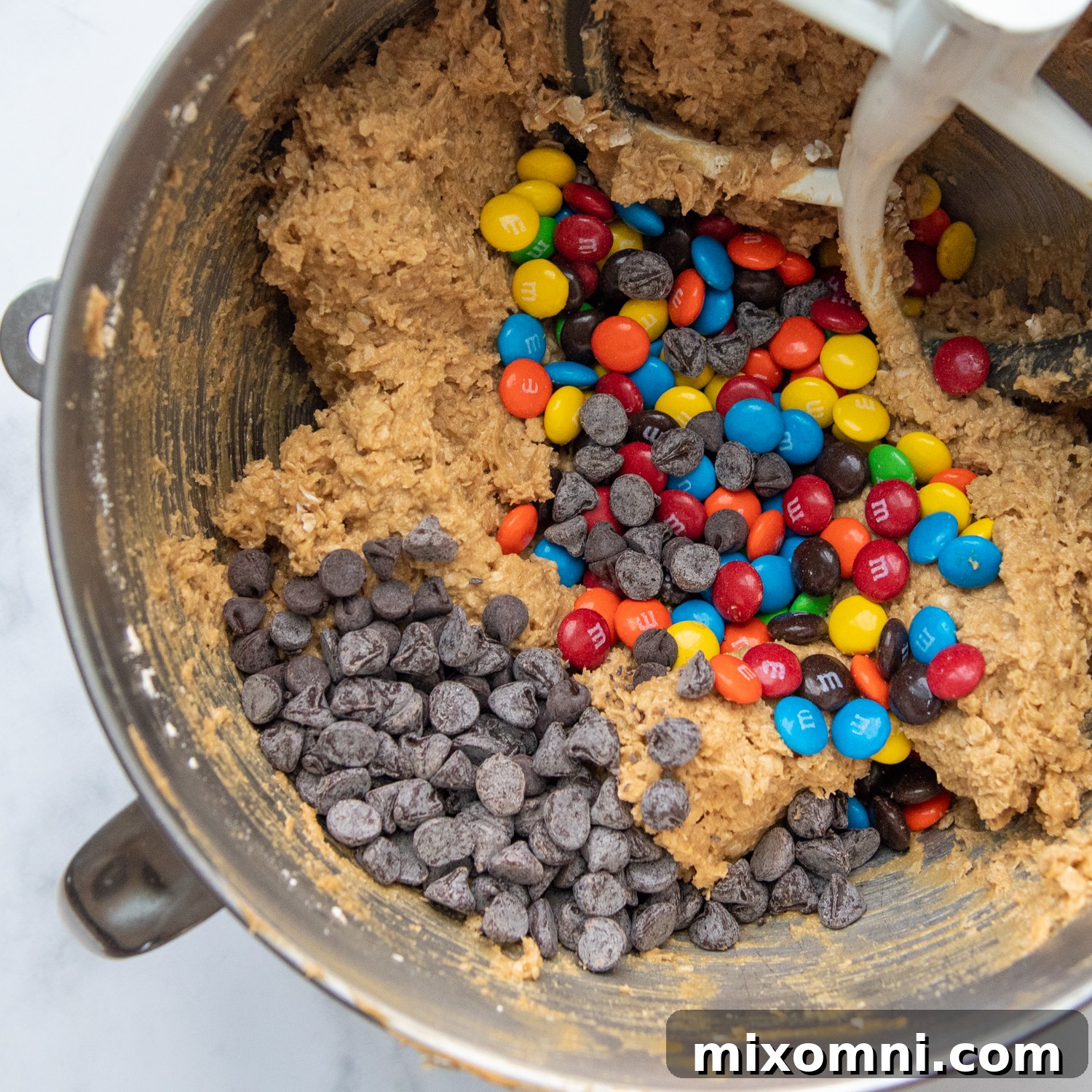 Gluten-free cookie dough generously studded with colorful M&M candies and rich chocolate chips, showcasing the delicious mix-ins.