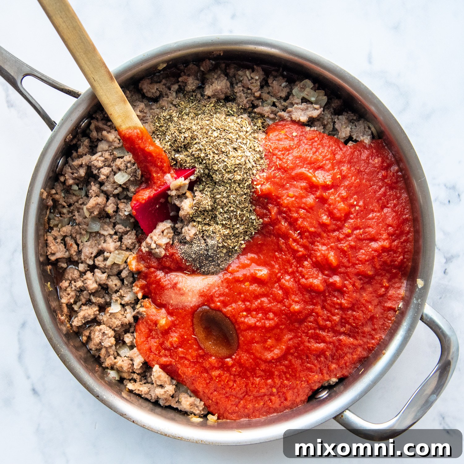The rich, simmering homemade lasagna sauce coming together in a large pan with ground meat, tomatoes, and aromatic herbs.