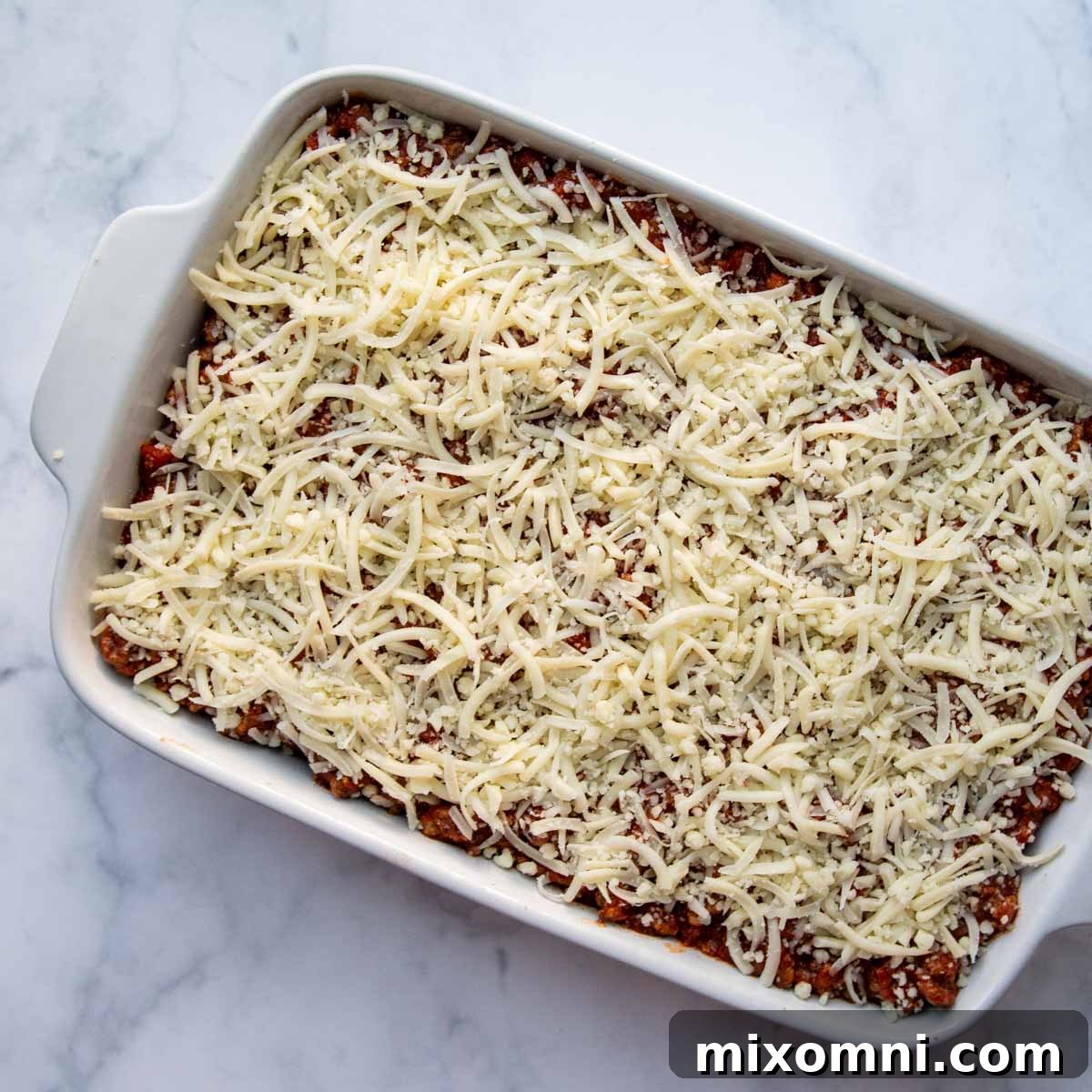 An overhead shot of an unbaked gluten-free lasagna in a baking dish, perfectly layered and ready for the oven, hinting at the delicious meal to come.