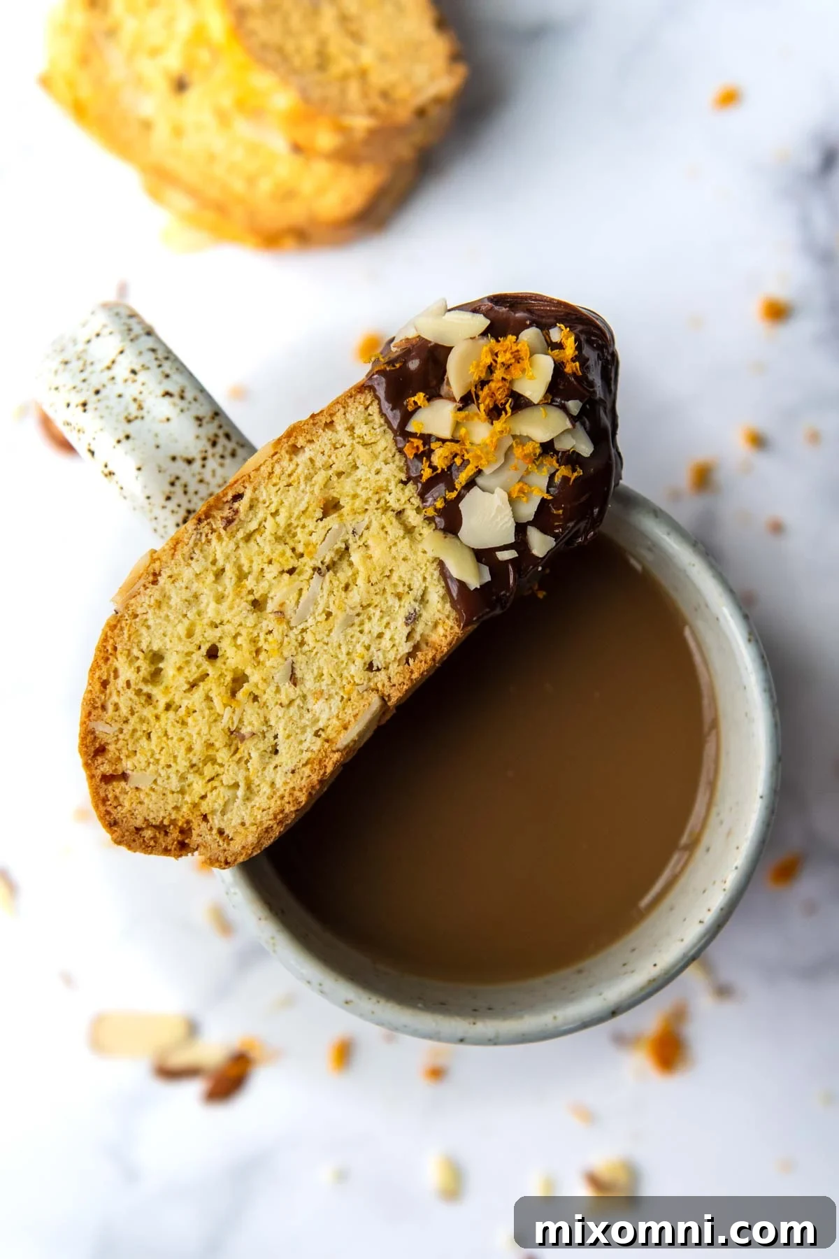 a gluten-free biscotti dipped in chocolate resting on top of a coffee cup