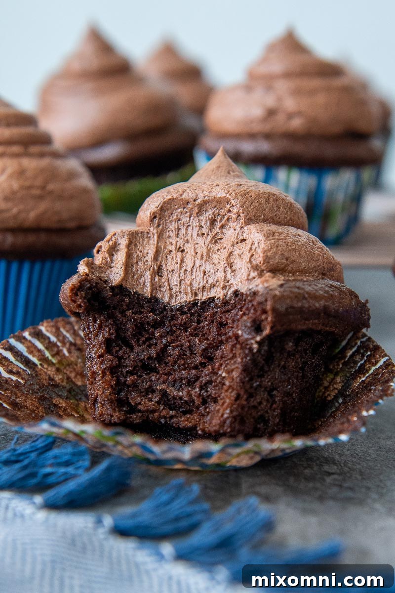 a gluten free chocolate cupcake unwrapped with a bite taken out, showing a moist, rich crumb