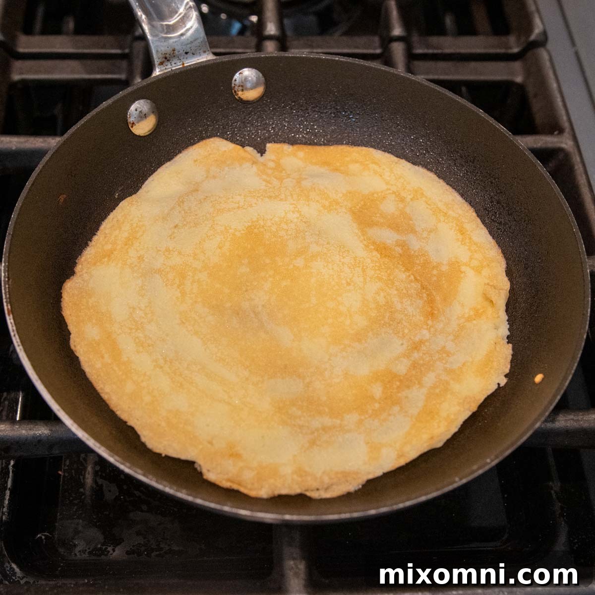 A freshly cooked gluten-free crepe resting in a skillet, displaying a golden-brown surface.