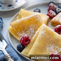 Close-up of folded gluten-free crepes with berries scattered around.