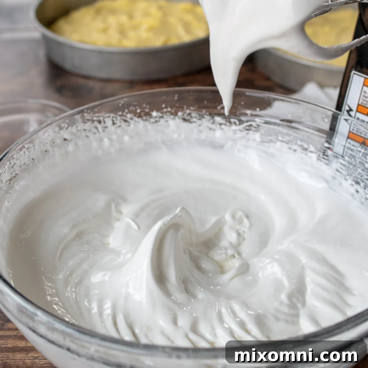 Stiff, glossy peaks of meringue in a clear glass bowl.