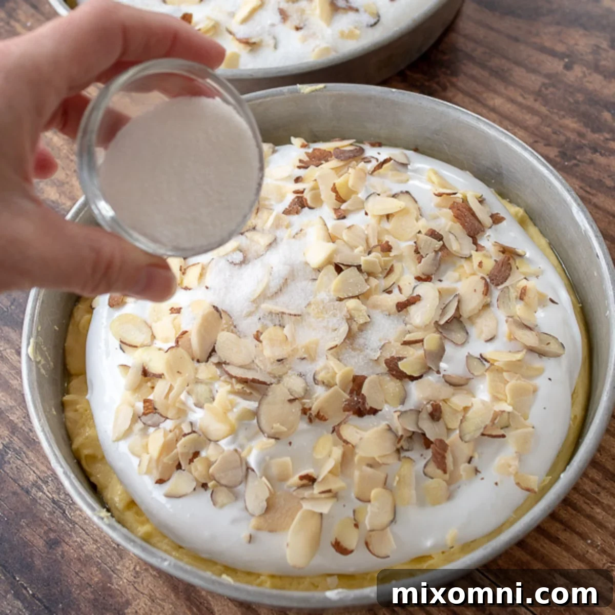 Granulated sugar sprinkled on sliced almonds atop the meringue layer before baking.