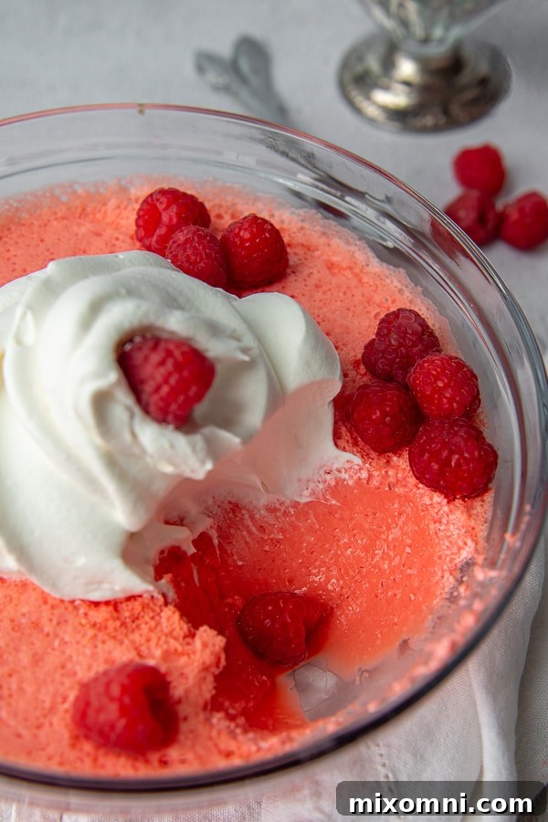 A scoop of vibrant jello salad, creamy and refreshing, taken from a serving bowl and placed on a plate, showcasing its delightful texture.