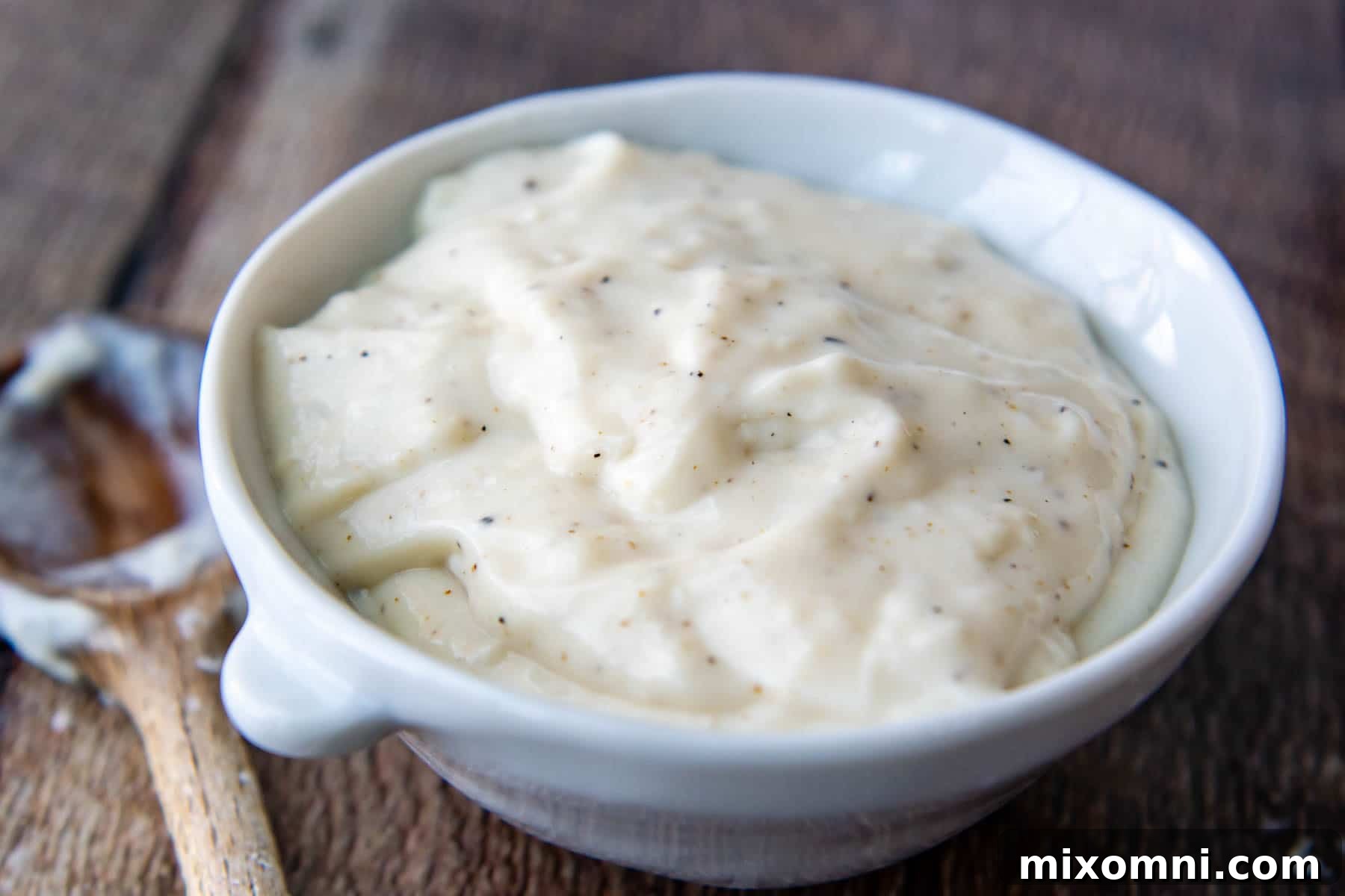 a white bowl with condensed cream of chicken soup and a wooden spoon laying next to it